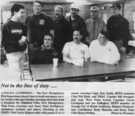 Newspaper clipping of several men posing at a table inside a firehouse